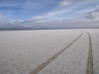 two tires are visible in this large open plain in front of clouds, with mountains in the distance