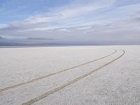 two tires are visible in this large open plain in front of clouds, with mountains in the distance