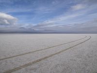 two tires are visible in this large open plain in front of clouds, with mountains in the distance