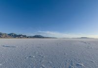 a wide expanse filled with snow and covered in mountains in the distance on a clear day