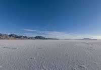 a wide expanse filled with snow and covered in mountains in the distance on a clear day