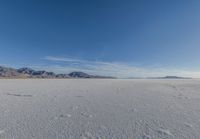 a wide expanse filled with snow and covered in mountains in the distance on a clear day