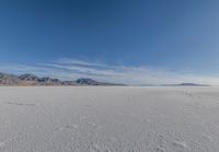 a wide expanse filled with snow and covered in mountains in the distance on a clear day