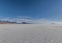 a wide expanse filled with snow and covered in mountains in the distance on a clear day