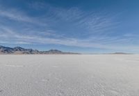 a wide expanse filled with snow and covered in mountains in the distance on a clear day