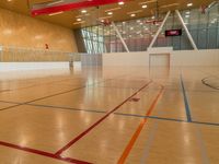 an indoor gym with wood floor and basketball court in background with windows and a television above