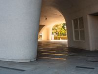 a man is riding his skateboard under an archway on the side walk of a building