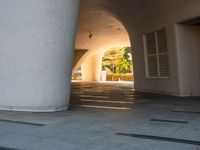 a man is riding his skateboard under an archway on the side walk of a building