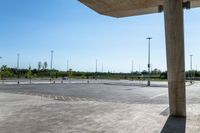 an empty parking lot with a few cars and people walking on it around it and buildings in the background