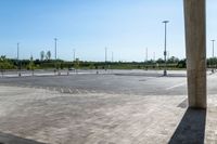 an empty parking lot with a few cars and people walking on it around it and buildings in the background