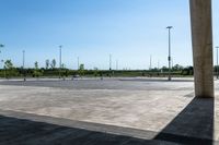 an empty parking lot with a few cars and people walking on it around it and buildings in the background