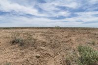 dirt field with a sky and cloud in the background and blue skies overhead over it