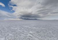 a landscape is shown with large clouds in the distance and a mountain on the horizon