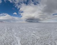 a landscape is shown with large clouds in the distance and a mountain on the horizon