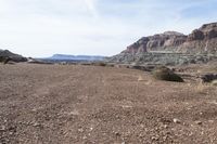 a dirt road with mountains in the background and some rocks on both sides of the road