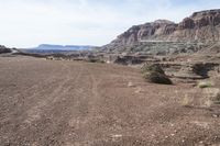 a dirt road with mountains in the background and some rocks on both sides of the road