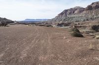 a dirt road with mountains in the background and some rocks on both sides of the road