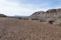 a dirt road with mountains in the background and some rocks on both sides of the road