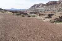 a dirt road with mountains in the background and some rocks on both sides of the road