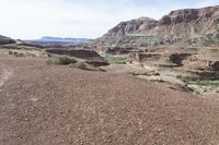 a dirt road with mountains in the background and some rocks on both sides of the road