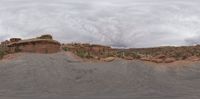 a view from the beach looking at a distant area of land beyond and the desert with mountains and a red rock