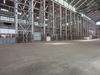 a empty warehouse floor with a lot of windows and metal structures that support workers on the ceiling