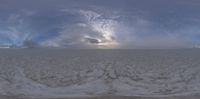 a large open air field with lots of snow on top and sky behind it as seen through a fisheye lens