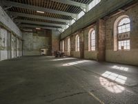 a large empty warehouse with many windows and chairs in the middle of it, and a fire place