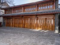 an oriental style building has wooden doors and windows on each floor, along with a walkway leading to the front entrance