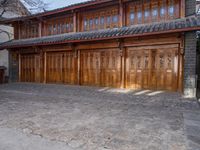 an oriental style building has wooden doors and windows on each floor, along with a walkway leading to the front entrance