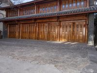 an oriental style building has wooden doors and windows on each floor, along with a walkway leading to the front entrance