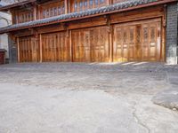 an oriental style building has wooden doors and windows on each floor, along with a walkway leading to the front entrance