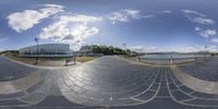 a 360 degree view of a small park across from an ocean and the sea on a sunny day