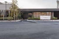 a man skateboarding along a paved parking area outside a building with landscaping and trees