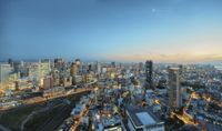 a large city with many tall buildings and streets at dusk on top of it near a highway