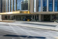 street sign sitting next to grass and sidewalk in front of building with windows and parking lot behind it