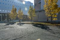 street with empty parking space next to building in open area and trees in foreground