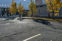 street with empty parking space next to building in open area and trees in foreground