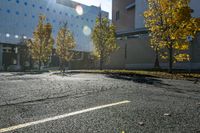 street with empty parking space next to building in open area and trees in foreground