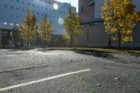 street with empty parking space next to building in open area and trees in foreground