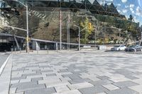 a square stone patio with a building in the background with the sky reflected in the building