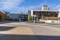 an empty plaza surrounded by tall buildings on a sunny day with the sky in the background