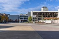 an empty plaza surrounded by tall buildings on a sunny day with the sky in the background