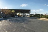 the view of a road with cars parked under an overpass next to it with a street light