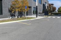 an empty parking lot next to a building in autumn season - image, taken from the sidewalk