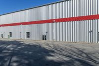 the large steel building has red and silver walls on it's sides, while other windows have been put in