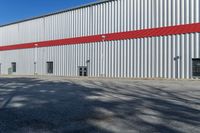 the large steel building has red and silver walls on it's sides, while other windows have been put in