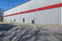 the large steel building has red and silver walls on it's sides, while other windows have been put in