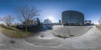 a street with a building and green trees in the background from fish eye lens to a full angle