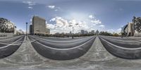 a fish eye lens shot of some buildings and clouds in the background, and a sky with many clouds